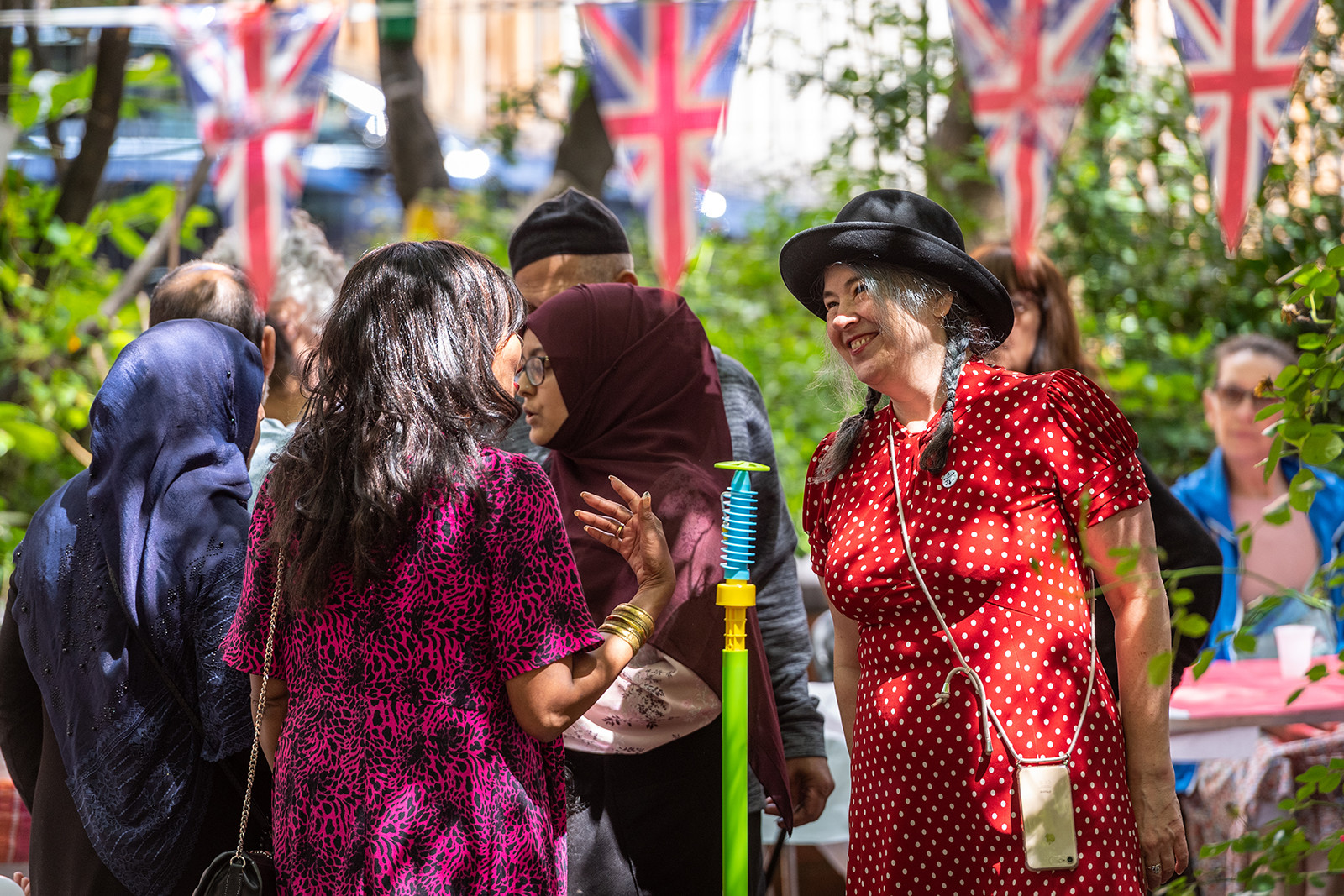 Some people chatting outside on a summer’s day, with Union Jack bunting hung above them.